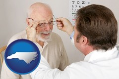 north-carolina map icon and an optician fitting eyeglasses on an elderly patient