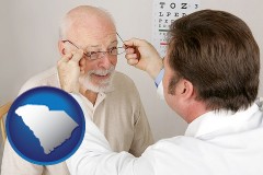 south-carolina map icon and an optician fitting eyeglasses on an elderly patient