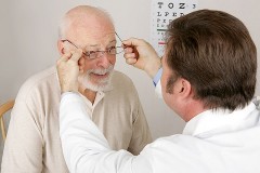 an optician fitting eyeglasses on an elderly patient
