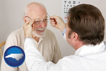 an optician fitting eyeglasses on an elderly patient - with North Carolina icon